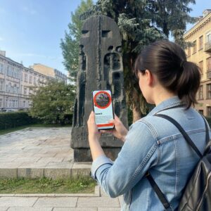 A woman plays a city game on her phone in front of the Monument to the Victims of the Ghetto in Lublin.