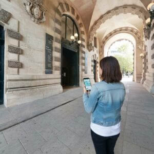 A woman looks at a map on her phone while standing under an arcade at the Musée National de la Marine in Paris.