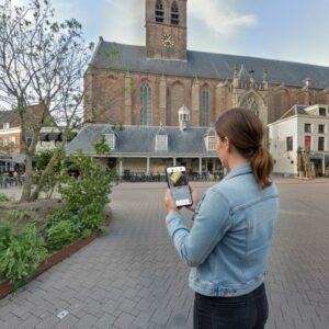 A woman plays a city game on her phone in a square before the Sint-Joriskerk in Amersfoort.