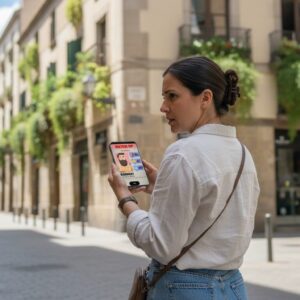 A woman looks over her shoulder while holding a smartphone on a narrow, historic street in Como.