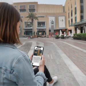 A woman sits in the City Walk plaza in Dubai, playing the Sherlock city game on her smartphone.