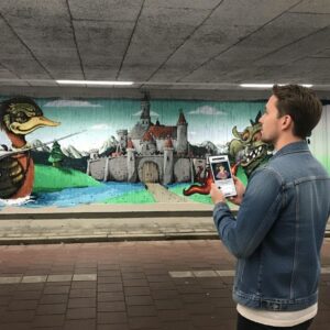A man looks at a large fantasy-themed graffiti mural in the Berenkuil underpass in Eindhoven.
