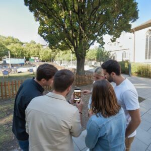 A group of five friends gathered outdoors in Essen, looking together at a smartphone screen.