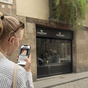 A young woman with a blonde braid plays a Sherlock-themed city game on her phone in Girona.