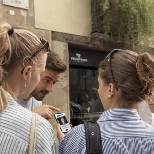 A group of young friends gather around a smartphone while playing a city exploration game in Kiruna.