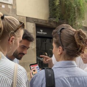 A group of four young friends looks at a smartphone while playing a city exploration game together in Antwerp.