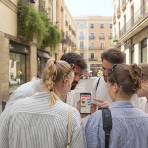 A group of five young friends gather around a smartphone while playing a city exploration game in Innsbruck.