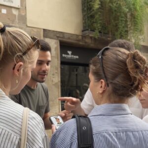 A group of young friends gather around a smartphone while playing an outdoor city game in Leiden.