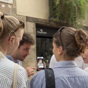 A group of four young friends stand together on a street in Liverpool, looking at a smartphone.