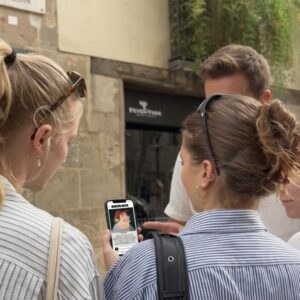 A group of young friends gathered on a street in Nicosia, looking at a city game on a smartphone.