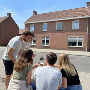 A group of five young adults gather on a sunny sidewalk in Almere, looking at a smartphone.