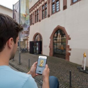 A man plays a city game on his phone on a cobblestone street in front of the Historical Museum in Frankfurt.