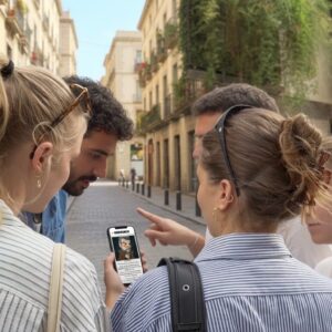 A group of young friends look at a smartphone while playing a city game on a street in Pisa.