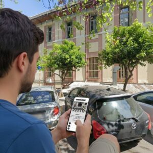 A young man playing the Sherlock city game on his smartphone on a sunny street in Heraklion.