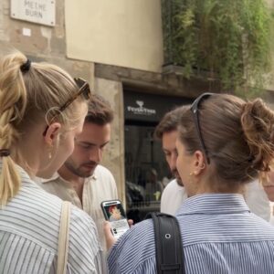 A group of young friends gathered on a street in Pula, looking at a smartphone together.