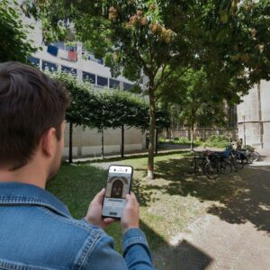 A person plays a city game on their smartphone near the Grote of Sint-Laurenskerk church in Rotterdam.
