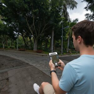 A young man sits in a park in Santa Cruz de Tenerife playing a Sherlock-themed game on his smartphone.