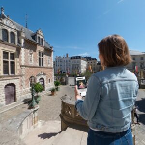 A player holds a phone displaying the Sherlock game in front of the Hôtel Groslot in Orleans.