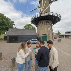 A group of young people looks at a smartphone in front of the De Hoop windmill in Hellevoetsluis.
